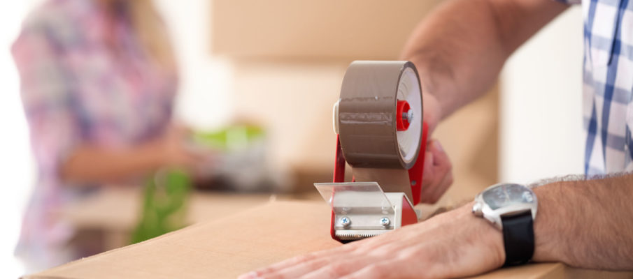 close up of male hand packing cardboard box